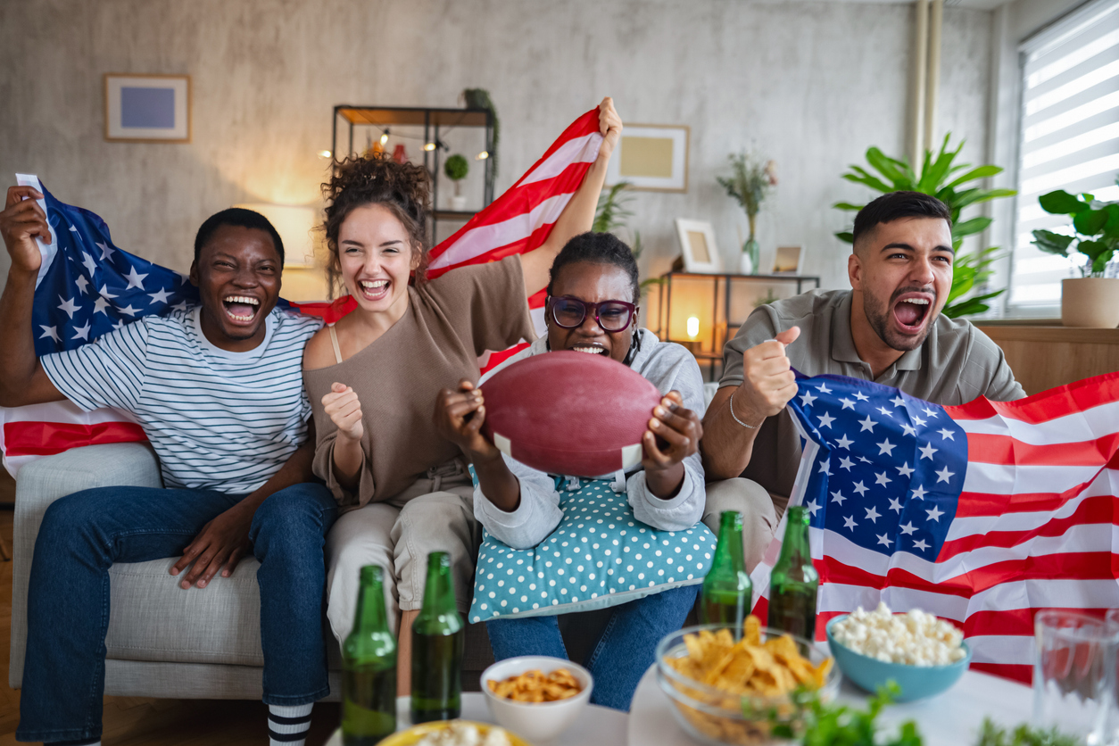 Excited friends cheering and watching american football match at home