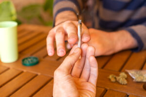 People sitting on a table during a party sharing a cannabis joint.