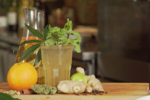 A healthy drink made of lime, ginger, and cannabis on a wooden surface