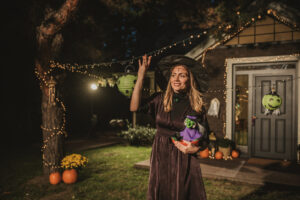 Woman disguised as a witch preparing sweets for kids at the door of her house on Halloween.